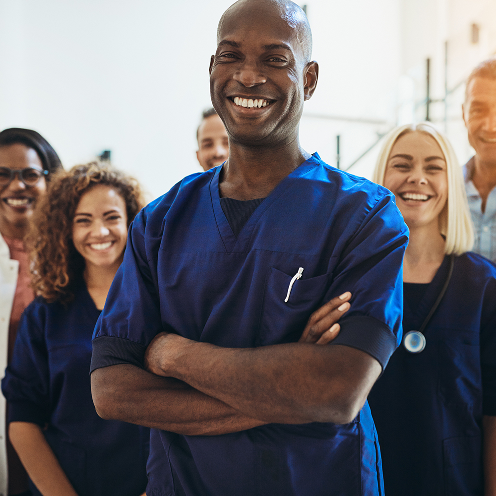 Smiling African doctor standing in a hospital with his staff